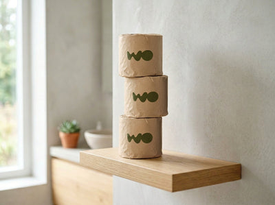 Unbleached beige bamboo toilet paper rolls stacked on a bright minimalist bathroom shelf